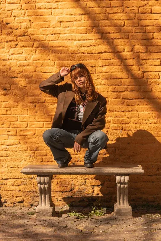 Retrato urbano para web: joven sentada frente a una pared amarilla en CABA
