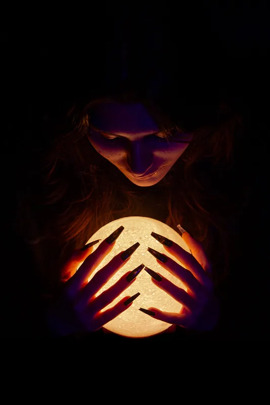 Fotografía conceptual para web: mujer iluminada por una bola de cristal en estudio